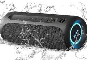 A portable Bluetooth speaker with water splashing around it, indicating its water resistance. The speaker is cylindrical with a mesh covering and control buttons on the top. A glowing ring light and the brand name 