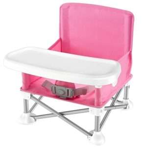 A pink portable restaurant high chair with a white tray and safety harness, featuring a foldable metal frame for easy transport. Ideal for dining out with young children.